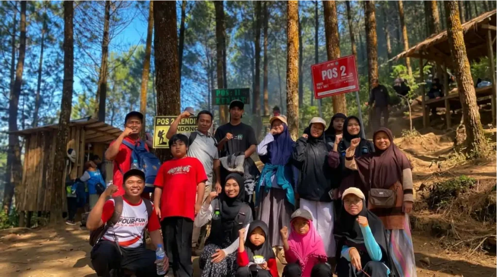 Peserta Andong Peak Journey PKS Kecamatan Ambarawa berfoto bersama di kawasan Pos 2 jalur Pendem Gunung Andong, Kabupaten Semarang, dengan latar hutan pinus dan papan penanda pos pendakian.